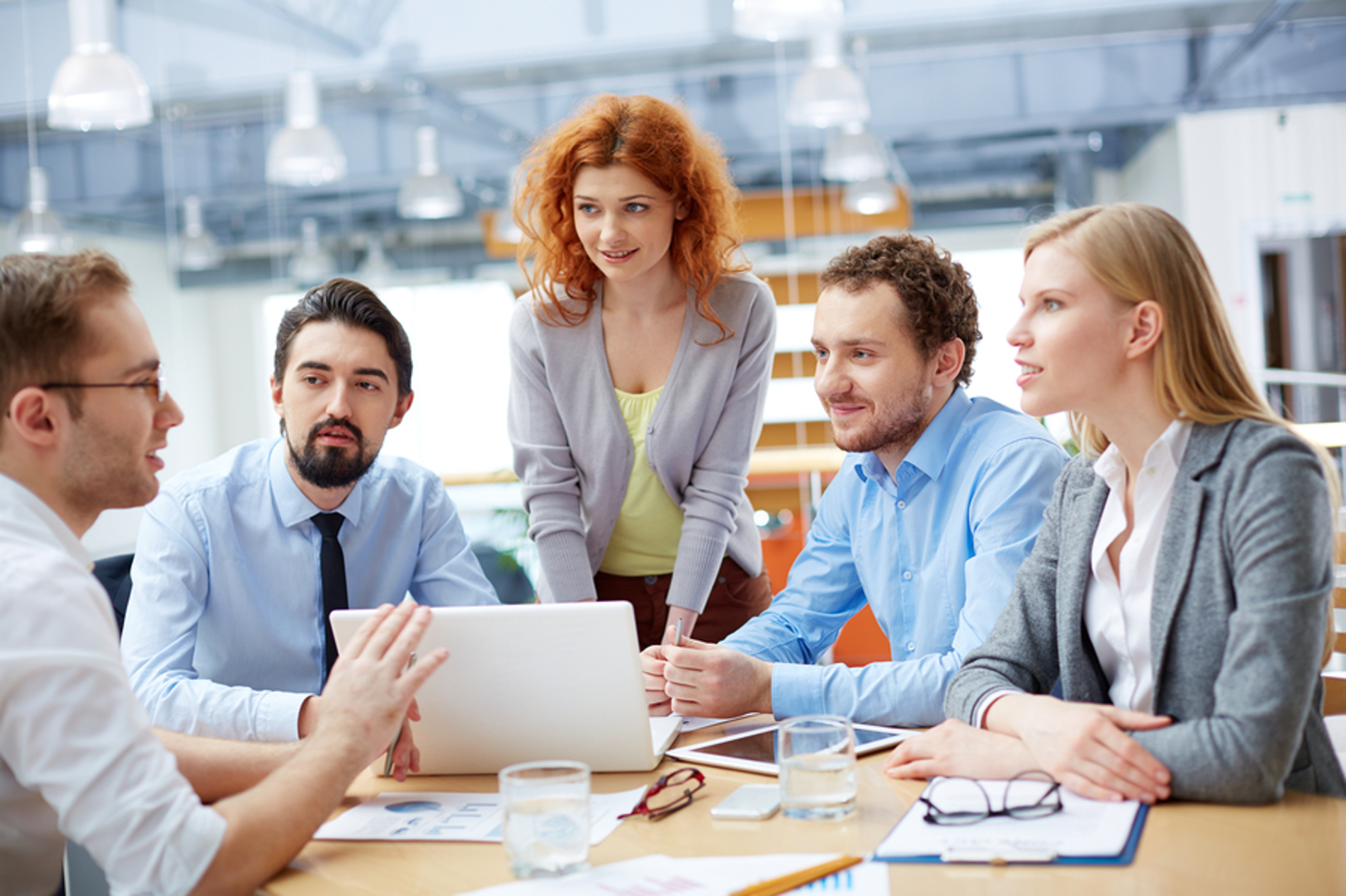 Group of people meeting around a table with a laptop.